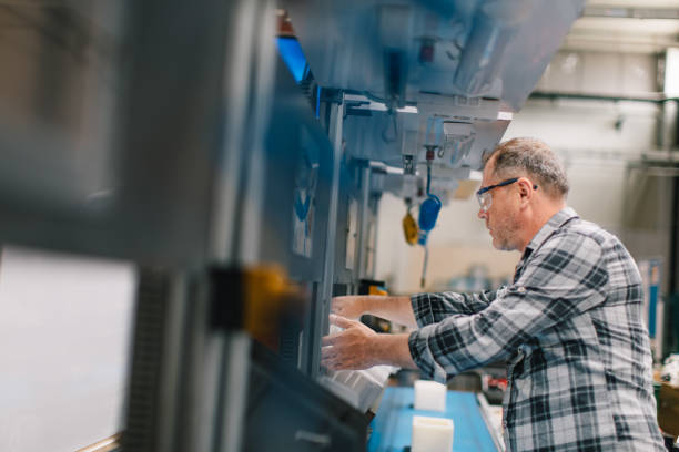Professional mature industrial factory male employee concentrated, working, putting, checking and testing with product line of industrial equipment cables manufacturing plant in large electronics factory warehouse