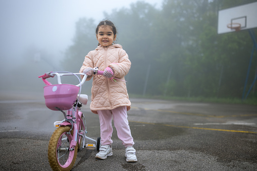 Portrait of little Hispanic girl riding a bike outdoors