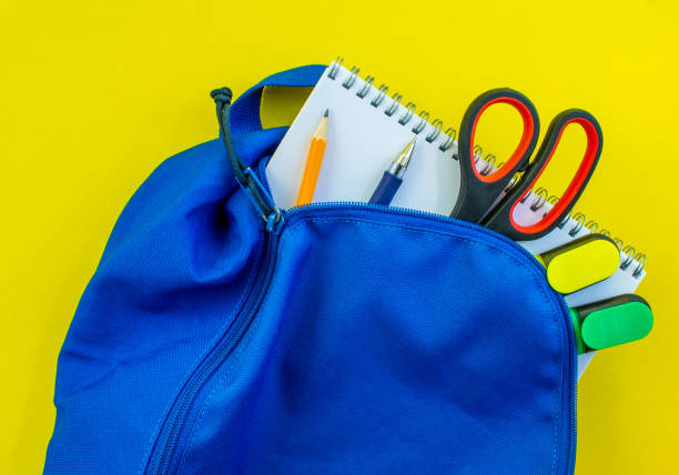 istock School backpack, pencil, pen, markers, scissors and notepad on a yellow background. 1510801204