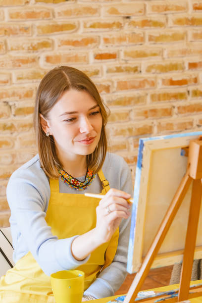 istock Woman with brush painting on canvas 1510820836