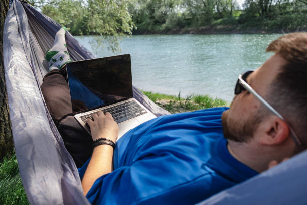 istock Relaxing work environment: man in hammock with laptop by river 1510820843