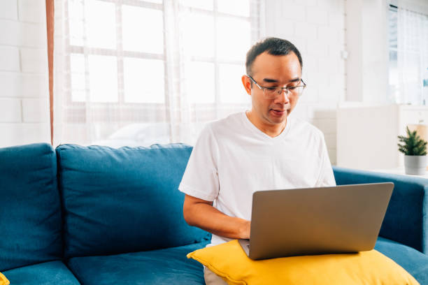 istock Cheerful man using laptop and surfing internet in living room 1510823573