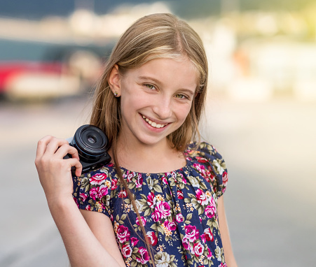 Beautiful little girl with camera, summer outdoor