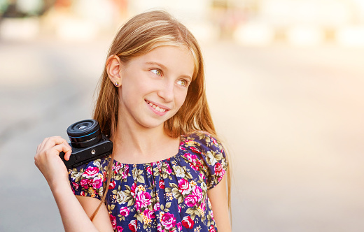 Beautiful little girl with camera, summer outdoor