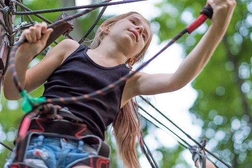 Girl hiking in the rope park in safety equipment