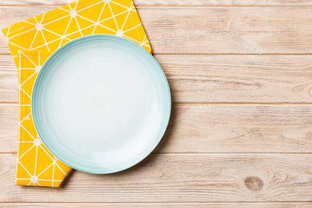 Top view on colored background empty round Blue plate on tablecloth for food. Empty dish on napkin with space for your design.