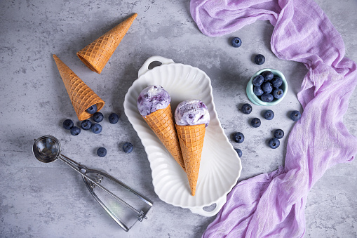 Blueberry ice cream cones on concrete background
