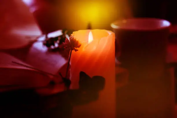 Photo of Candlelight in the dark, flowers,. Cozy evening at home. vintage toned. Burning candle. Atmospheric mood