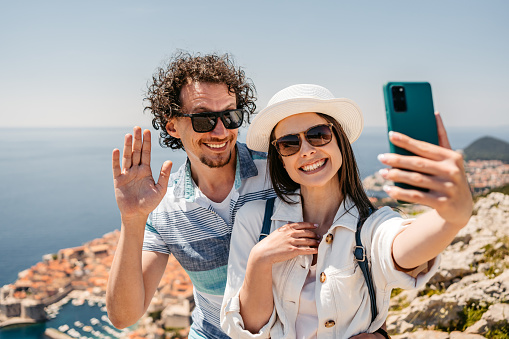 Young tourist couple having a video call at a high viewpoint of Dubrovnik in Croatia.