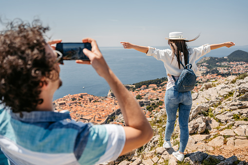 Boyfriend taking pictures of his girlfriend using phone at a high viewpoint of Dubrovnik in Croatia.