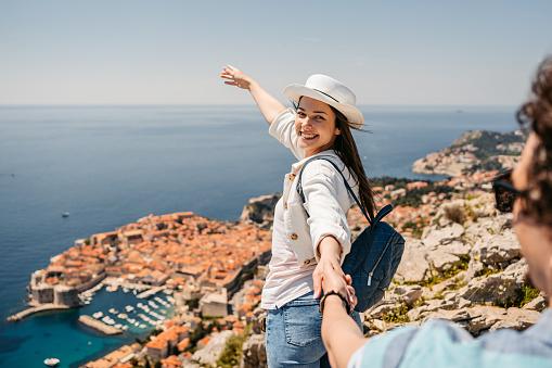 Young woman leading her boyfriend at a high viewpoint of Dubrovnik in Croatia.