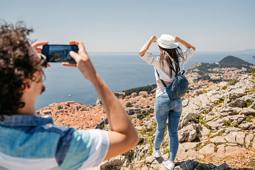Boyfriend taking pictures of his girlfriend using phone at a high viewpoint of Dubrovnik in Croatia.
