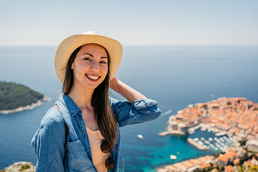 Portrait of a young female tourist standing at a high viewpoint above Dubrovnik in Croatia.