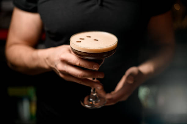 selective focus on crystal glass with tasty foamy cocktail decorated with coffee beans in male hands. - transparent holding glass focus on foreground imagens e fotografias de stock