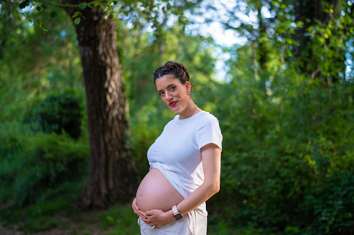 Beautiful young pregnant woman enjoying nature in the forest