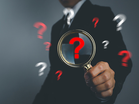 Businessman holding a magnifying glass with red question mark icon business question organization problem solving