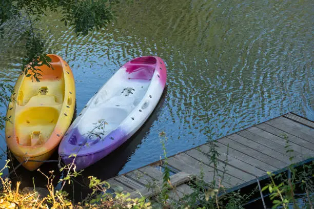 Two kayaks on a small homemade wooden jetty on a river during summer vacation.