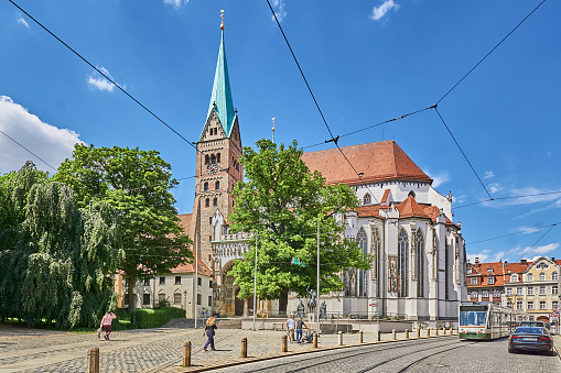 Augsburg, Germany - June 04, 2023: Pedestrians and trams in front of the Augsburg Cathedral.