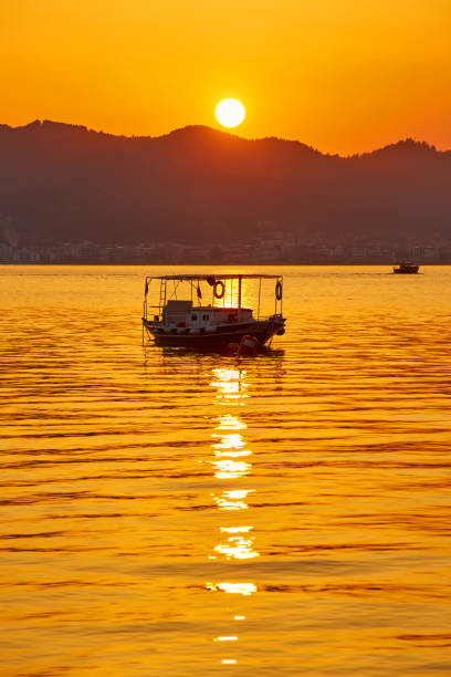 mountain and lonely motor boat reflected sunset in a calm sea, Marmaris, Turkey