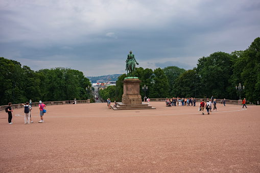 Oslo, Norway, June 20, 2023: Tourists visit the Royal Palace during a stormy day. It is where the monarchy works, the King presides over the Council of State and where the King and Queen live.
