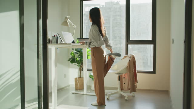 Businesswoman at standing desk home office talking on business video call