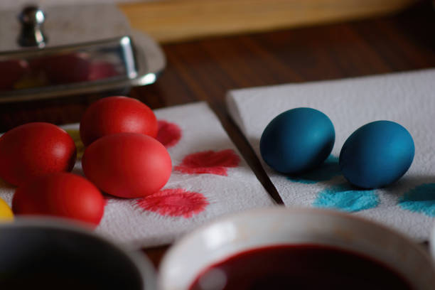 Painted eggs dry after painting on a paper napkin. Freshly baked homemade Easter bread, natural dyed eggs and spring flowers. Happy Easter. Stylish paska with sugar glaze and sprinkles, a traditional Ukrainian bun.