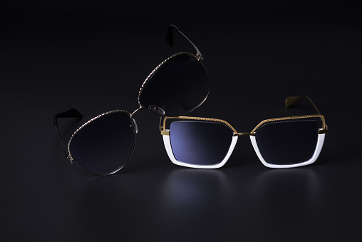 Close-up of two sunglasses isolated on a black studio background. Vision protection concept.