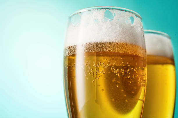 due bicchieri con birra schiumosa su sfondo azzurro. - beer bottle beer drinking pouring foto e immagini stock