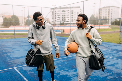Two friends arriving at basketball court, ready for picking up basketball