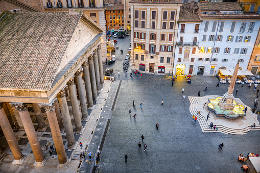 A suggestive evening scene of the majestic colonnade of the Roman Pantheon and Piazza della Rotonda seen from a terrace in the historic heart of Rome. Built in 27 BC by the Consul Marco Vispanio Agrippa for the emperor Augustus and dedicated to the Roman divinities, the majestic Pantheon is one of the best preserved Roman structures in the world. The fountain with the Egyptian obelisk in the center of the square was built by the sculptor Leonardo Sormani in 1575 on a project by the architect Giacomo della Porta. In 1980 the historic center of Rome was declared a World Heritage Site by Unesco. Wide angle image in high definition quality.