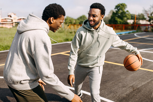 Two friends practicing basketball together on outdoor basketball court