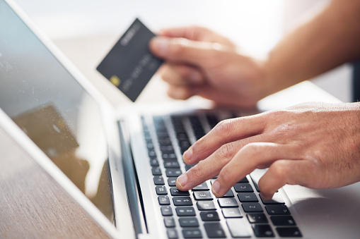 Hands, laptop and credit card for ecommerce, online shopping or electronic purchase on wooden desk. Hand of shopper working on computer keyboard for internet banking, app or wireless transaction