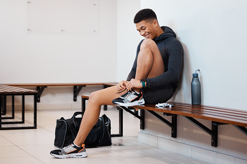 Fitness, tying shoes and black man in locker room for training, sports and gym workout. Exercise, health and start cardio with athlete and dressing sneakers for cardio, wellness or ready for practice