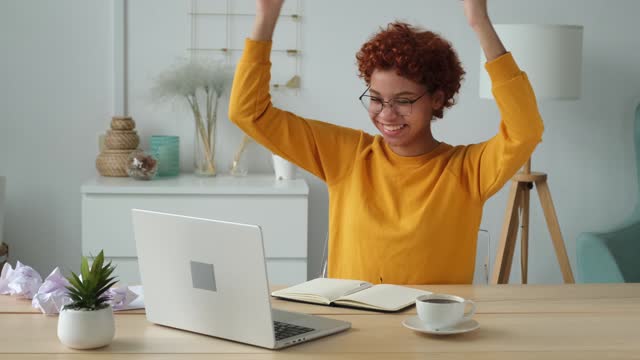 Excited happy african american woman winner. Girl female student looking at laptop passed exam reading great news getting good result winning online bid feeling amazed looking at computer at home.