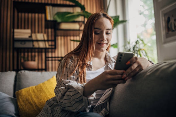 istock Beautiful woman sitting on the sofa and using smart phone 1511221367