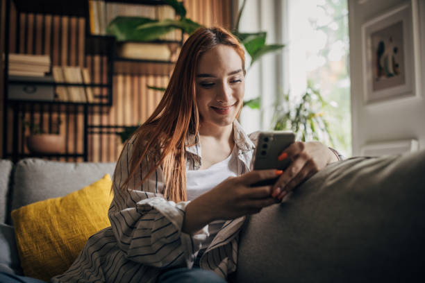 istock Beautiful woman sitting on the sofa and using smart phone 1511225234