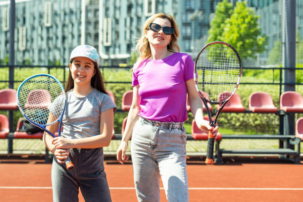 glückliche kaukasische mutter und tochter spielen tennis auf tennisplatz im freien - tennis court love victory stock-fotos und bilder
