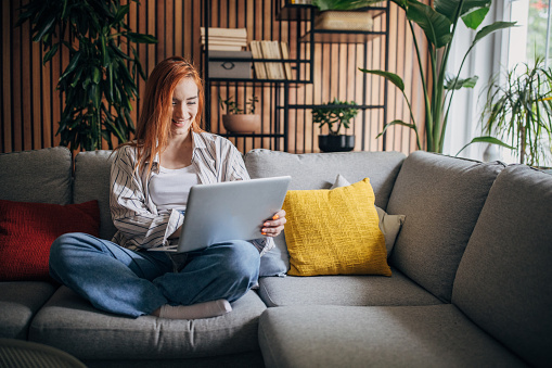 Redhead woman using laptop and relaxing at home