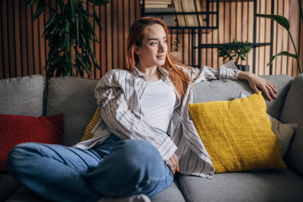 istock Young redhead woman sitting on the sofa and drinking coffee 1511240472