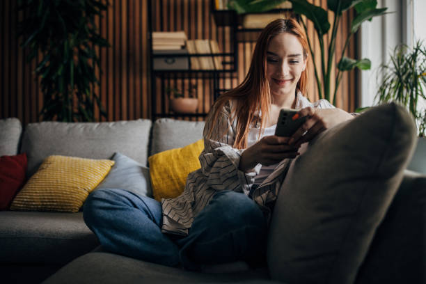 istock Beautiful woman sitting on the sofa and using smart phone 1511242774