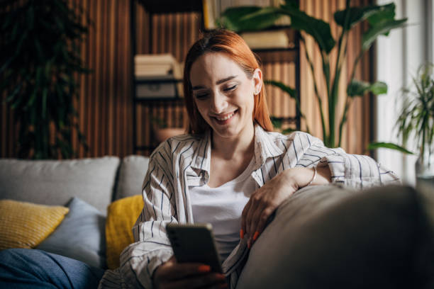 istock Beautiful woman sitting on the sofa and using smart phone 1511247972