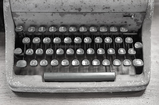 An antique vintage typewriter which is placed on wooden table, close-up and selective focus.