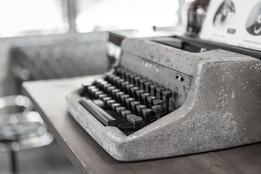 An antique vintage typewriter which is placed on wooden table, close-up and selective focus.
