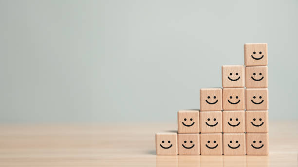 Happy smiling face icons on wooden block cubes. Business satisfaction experience rating survey and customer service teamwork concept. stock photo