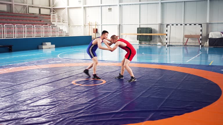 Colorful Wrestling Showdown: Red and Blue Singlet Wrestlers in Action