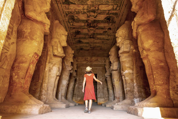 A young woman in a red dress at the Abu Simbel Temple next to the sculptures A young woman in a red dress at the Abu Simbel Temple next to the sculptures, in southern Egypt in Nubia next to Lake Nasser. Temple of Pharaoh Ramses II, travel lifestyle ramses i stock pictures, royalty-free photos & images