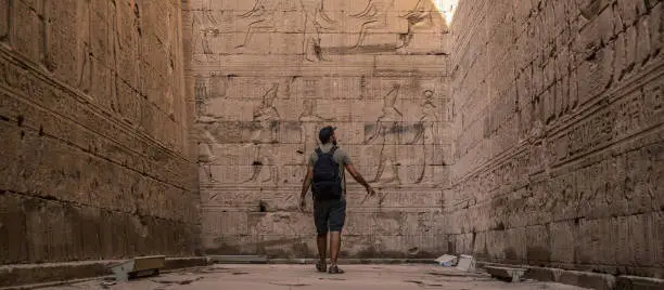 A young tourist visiting the beautiful temple of Edfu in the city of Edfu, Egypt. On the bank of the Nile river, geco-Roman construction, temple dedicated to Huros