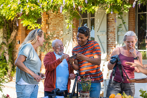 Group of diverse mixed age adults participating in a camera club outdoors in Toulouse in the South of France. They are using different cameras and a smart phone.