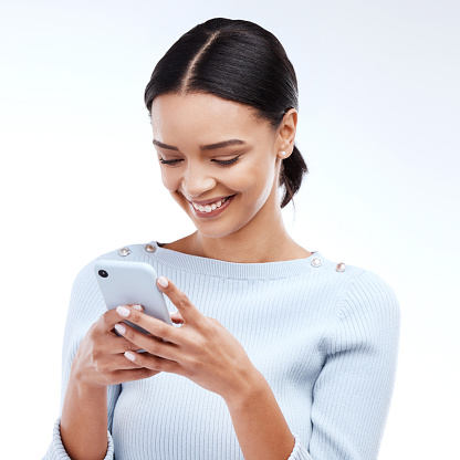 Phone, typing and happy woman isolated on a white background for social media, funny meme or internet chat. Young person networking, communication or reading internet post on mobile app in studio
