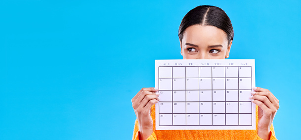Calendar, thinking and woman on blue background with poster for schedule, planning and agenda in studio. Time management, strategy and girl with month template for date, weekly planner and event